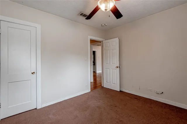 an empty room with chandelier fan and windows