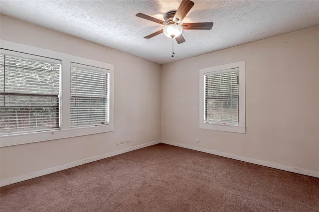 an empty room with a window and a ceiling fan