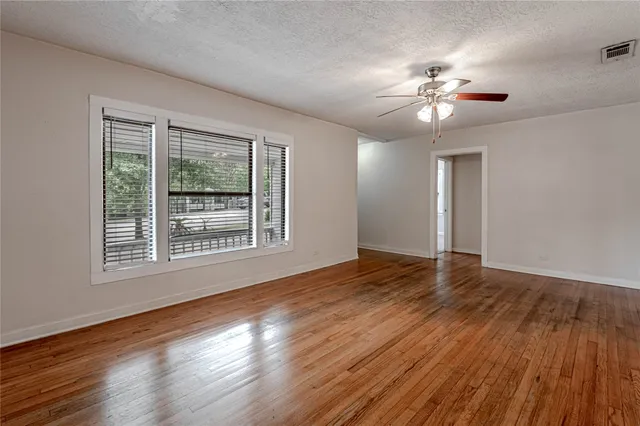 a view of an empty room with wooden floor and a window
