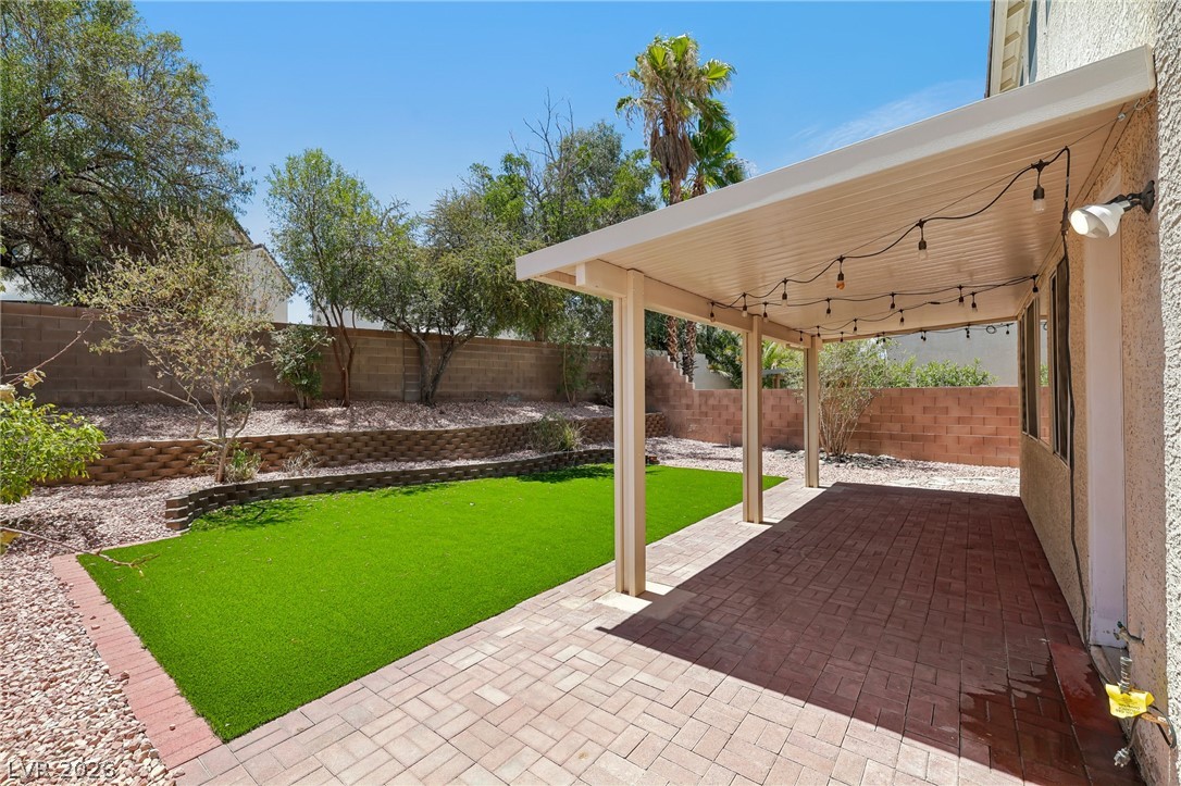 1727 Millstream Way Henderson, NV 89074 - Photo 45 of 46 A private backyard oasis features a paved patio area, covered for comfort, alongside a vibrant patch of synthetic turf.