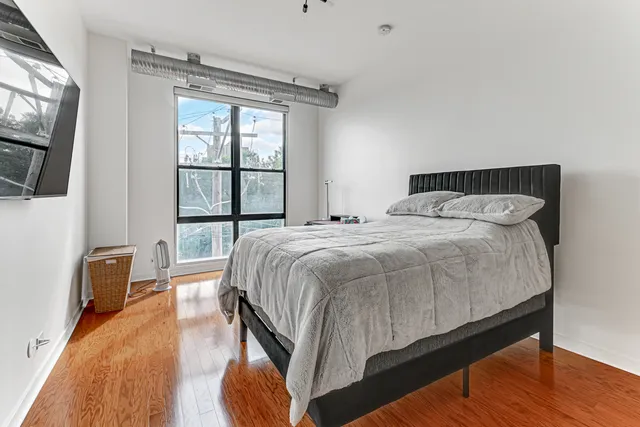 a bedroom with a bed a flat screen tv and next to a window