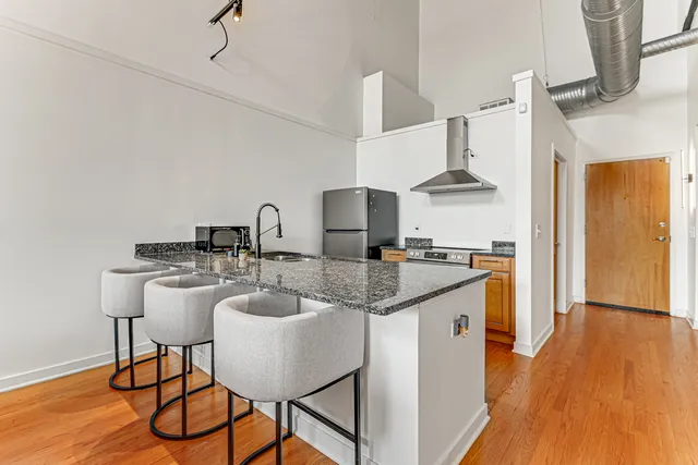 a kitchen with stainless steel appliances granite countertop a sink a stove and a wooden floor