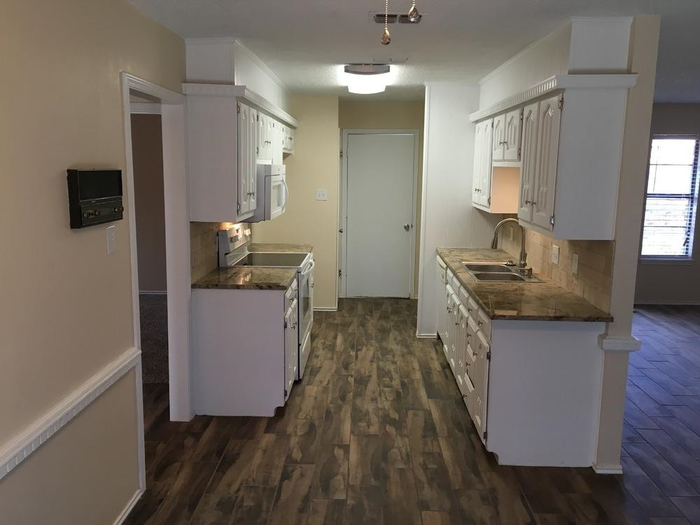 5739 Emory Street Lubbock, TX 79416 - Photo 2 of 10 a kitchen with granite countertop a sink and a stove top oven