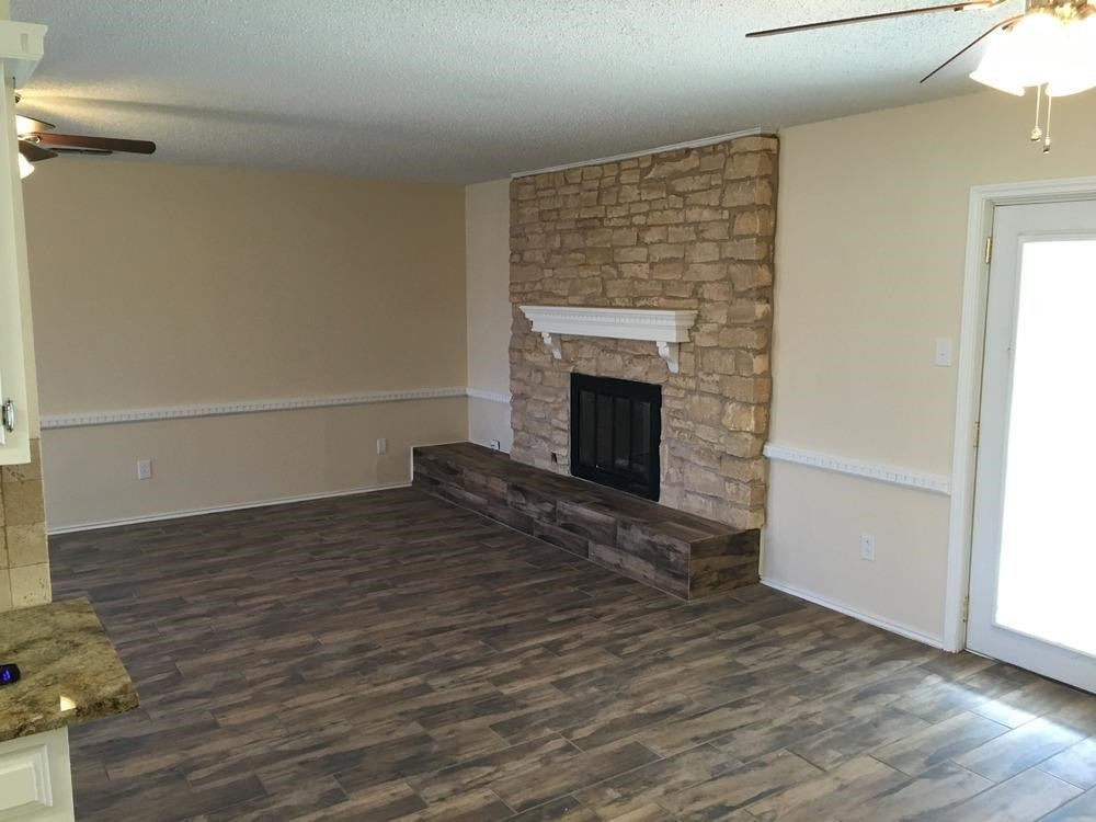5739 Emory Street Lubbock, TX 79416 - Photo 5 of 10 a view of empty room with wooden floor and fireplace