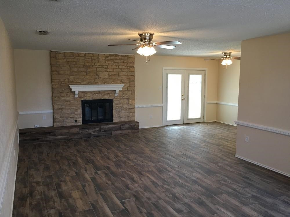 5739 Emory Street Lubbock, TX 79416 - Photo 7 of 10 a view of an empty room with wooden floor fireplace and a window