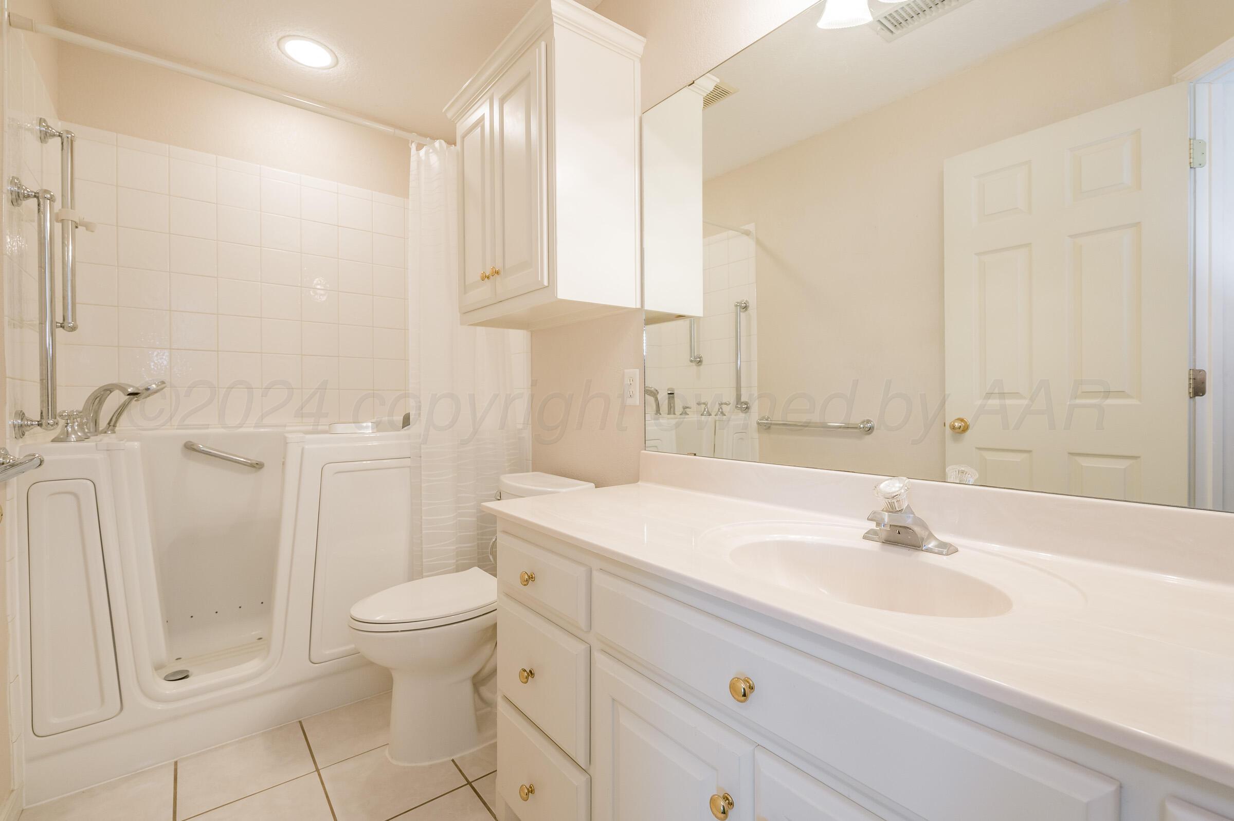 6308 Academy Drive Amarillo, TX 79119 - Photo 17 of 21 a bathroom with a sink a toilet and a large mirror