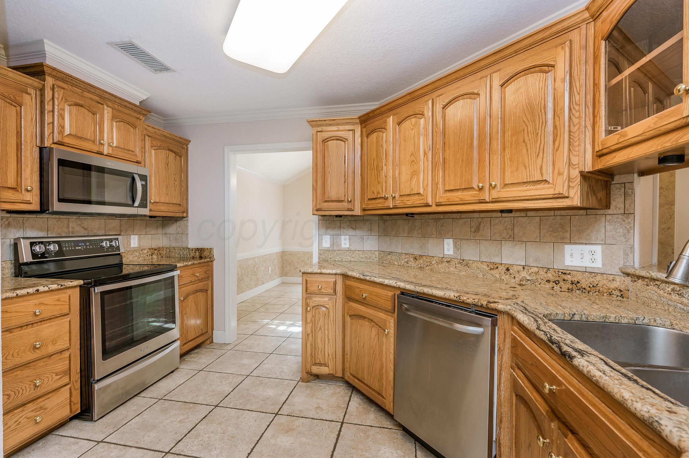 6308 Academy Drive Amarillo, TX 79119 - Photo 9 of 21 a kitchen with stainless steel appliances granite countertop a stove sink microwave and cabinets