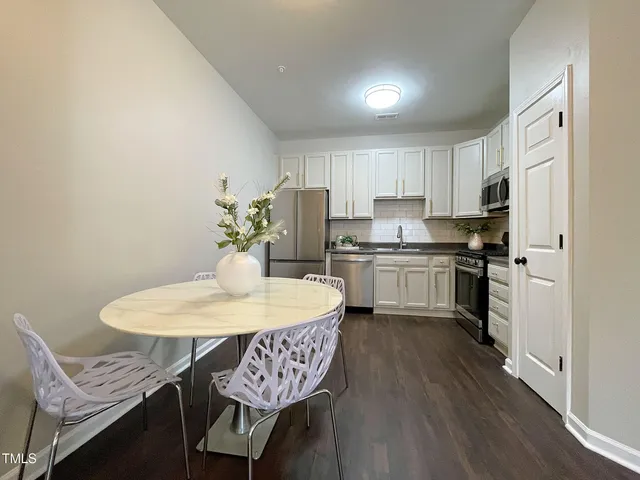 a kitchen with stainless steel appliances granite countertop a sink dishwasher a stove a refrigerator with a dining table and chairs