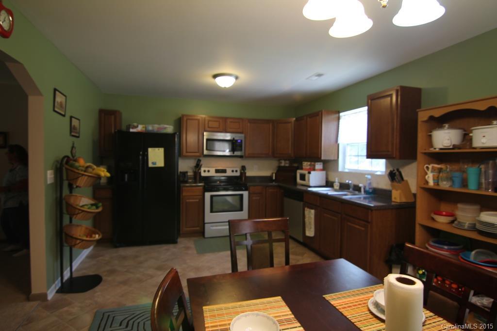 3807 White Store Road, Unit TRACT 1 W Wingate, NC 28174 - Photo 11 of 20 a kitchen with stainless steel appliances kitchen island granite countertop a refrigerator a stove a sink dishwasher and a dining table with wooden floor