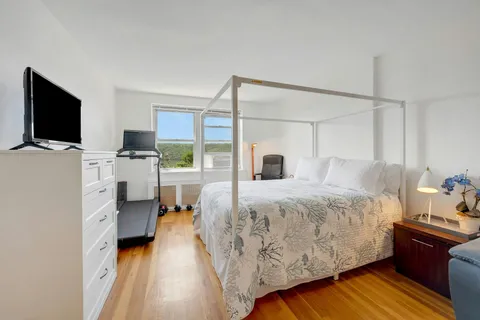 a bedroom with a bed and a flat tv screen on dresser