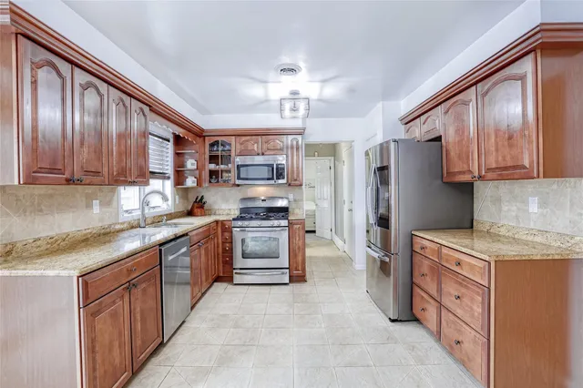 a kitchen with stainless steel appliances granite countertop a refrigerator a stove top oven a sink dishwasher and wooden cabinets