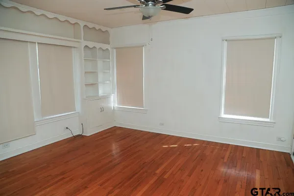a view of empty room with wooden floor and fan