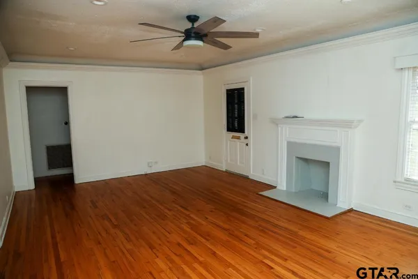 a view of empty room with wooden floor and fan