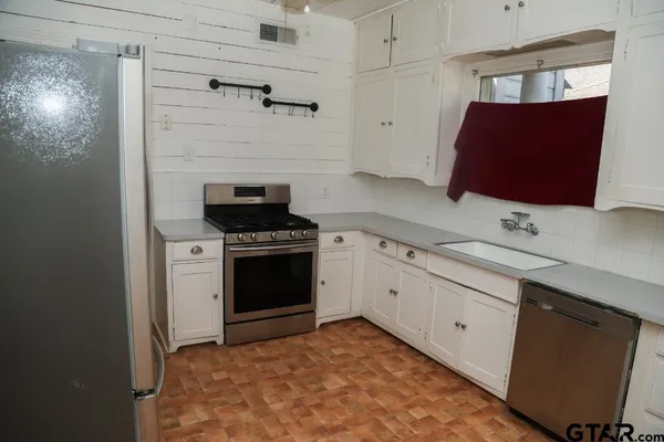 a kitchen with granite countertop a sink stainless steel appliances and cabinets
