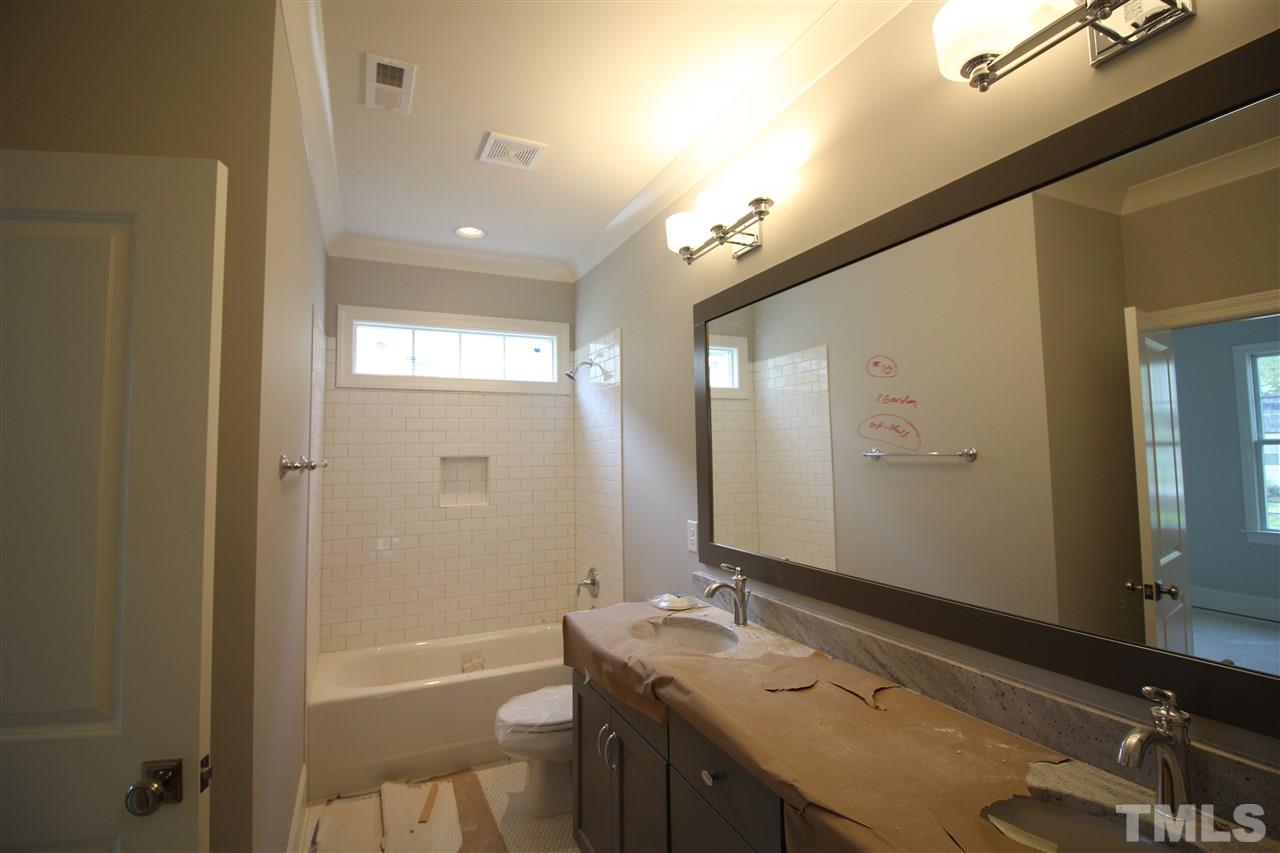 2705 1/2 Gordon Street Raleigh, NC 27608 - Photo 23 of 25 a bathroom with a granite countertop sink a mirror and a bathtub