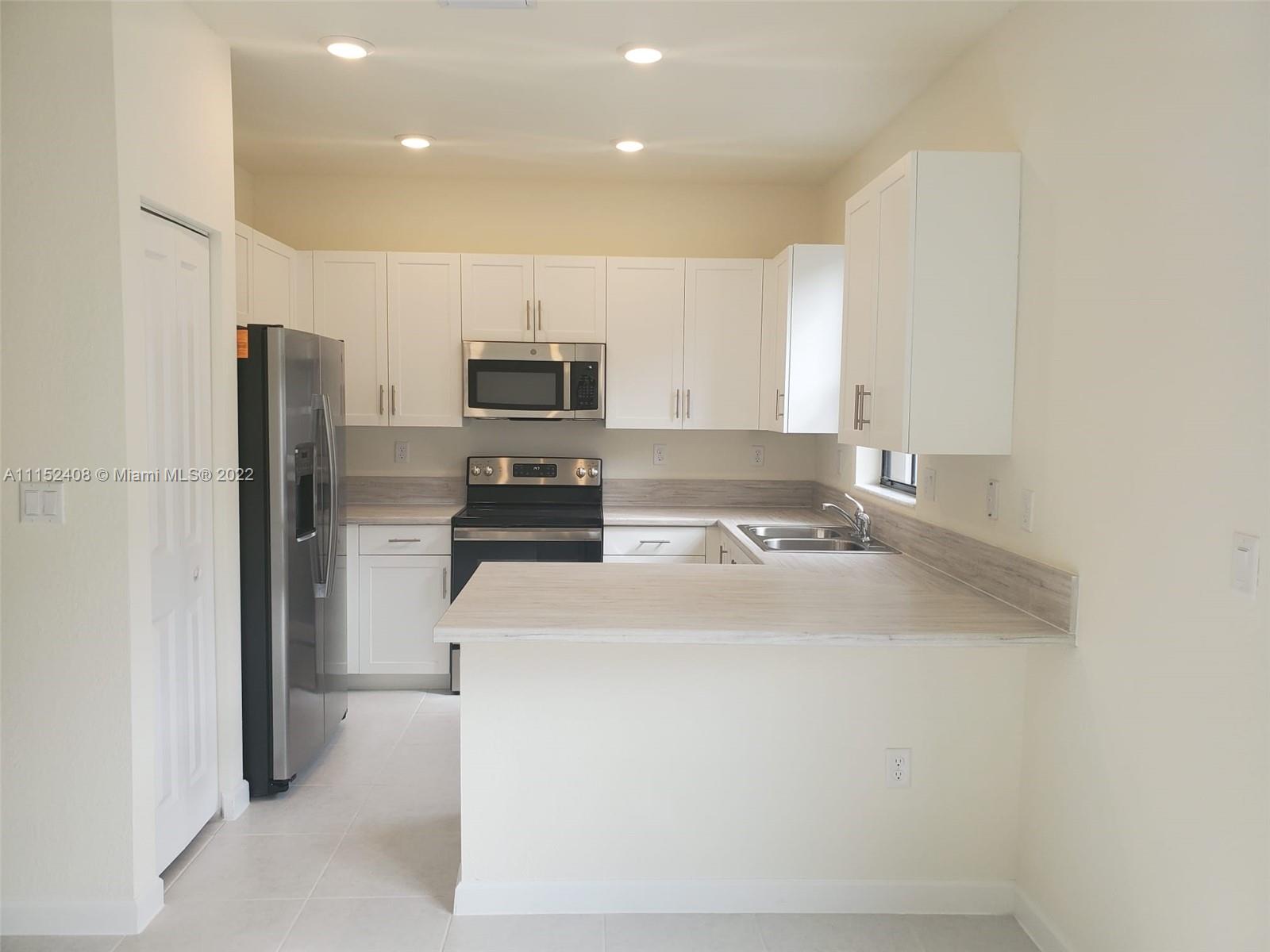 3326 West 112th Street, Unit 3326 Hialeah, FL 33018 - Photo 7 of 25 a kitchen with kitchen island a sink stainless steel appliances and cabinets