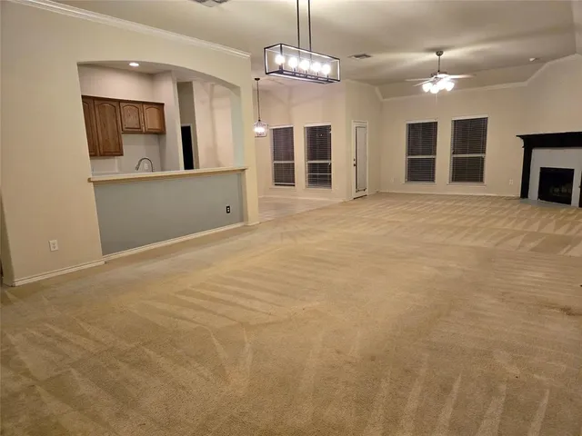 a view of an empty room with a fireplace and a chandelier