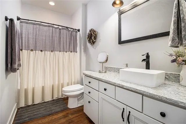 a bathroom with a granite countertop sink and a toilet