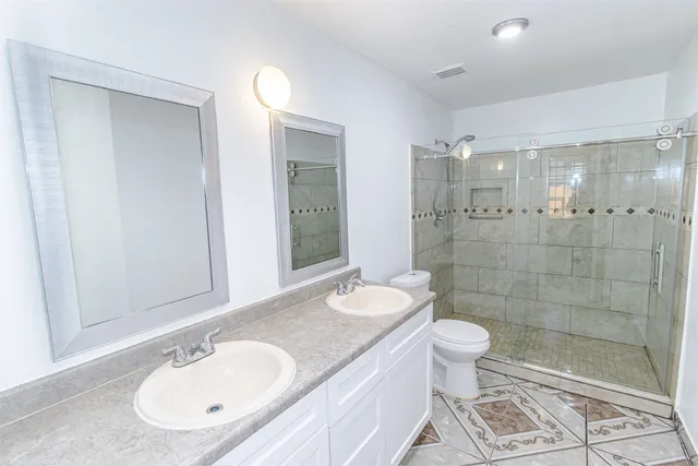 a bathroom with a granite countertop sink a toilet and shower