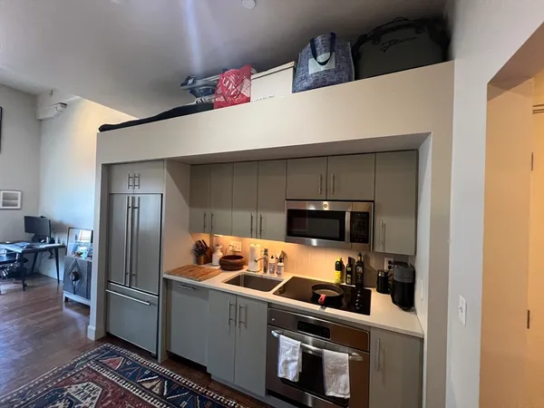 a kitchen with stainless steel appliances a refrigerator a stove and a refrigerator with wooden floor