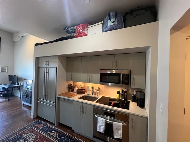 a kitchen with stainless steel appliances a refrigerator a stove and a refrigerator with wooden floor