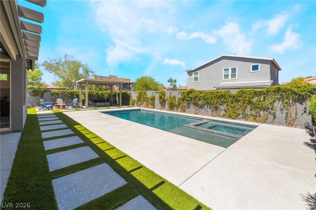 2166 Trivero Street Henderson, NV 89044 - Photo 43 of 61 An inviting backyard oasis offers a sparkling pool with an integrated spa, complemented by a covered patio space.