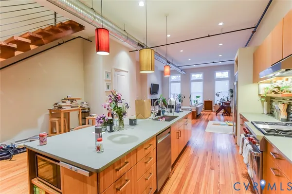 a very nice looking dining room with kitchen island granite countertop a large kitchen island a stove a sink a dining table and chairs with wooden floor