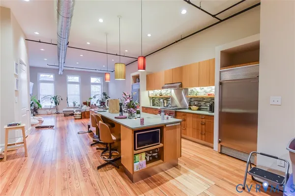 a kitchen with stainless steel appliances a stove top oven a refrigerator a sink and dining table with wooden floor