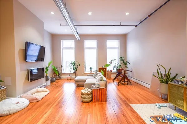 a living room with furniture a large window wooden floor and a rug