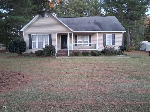 a view of a yard in front of a house with plants and large trees