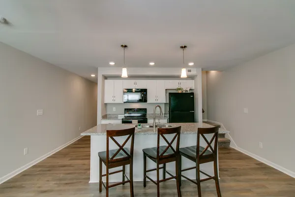 a kitchen with stainless steel appliances granite countertop a stove top oven a sink dishwasher a dining table and chairs with wooden floor