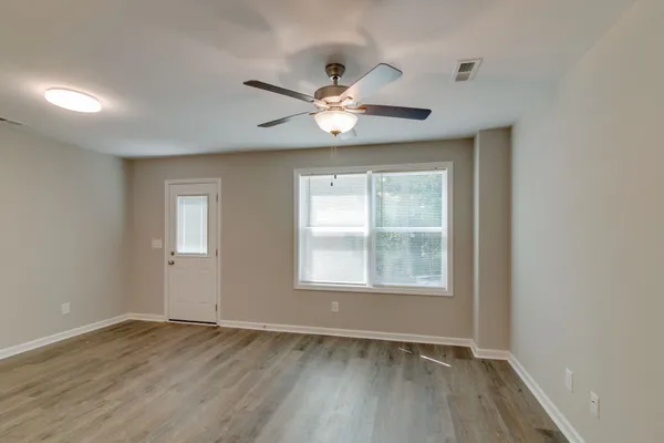 a view of an empty room with a window and a ceiling fan