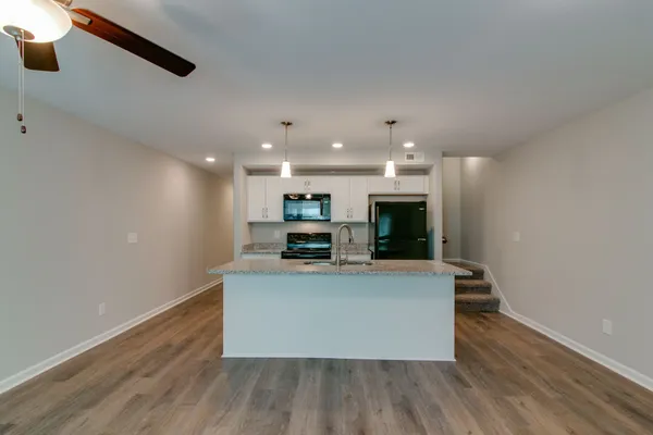 a kitchen with stainless steel appliances granite countertop a sink dishwasher a stove and a microwave oven with cabinets