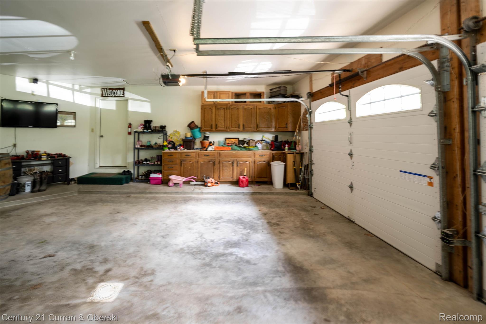 8775 Winding Rdg Drive Millersburg, MI 49759 - Photo 49 of 53 Spacious garage featuring a concrete floor, built-in cabinetry, overhead lighting, and two garage doors with arched window inserts