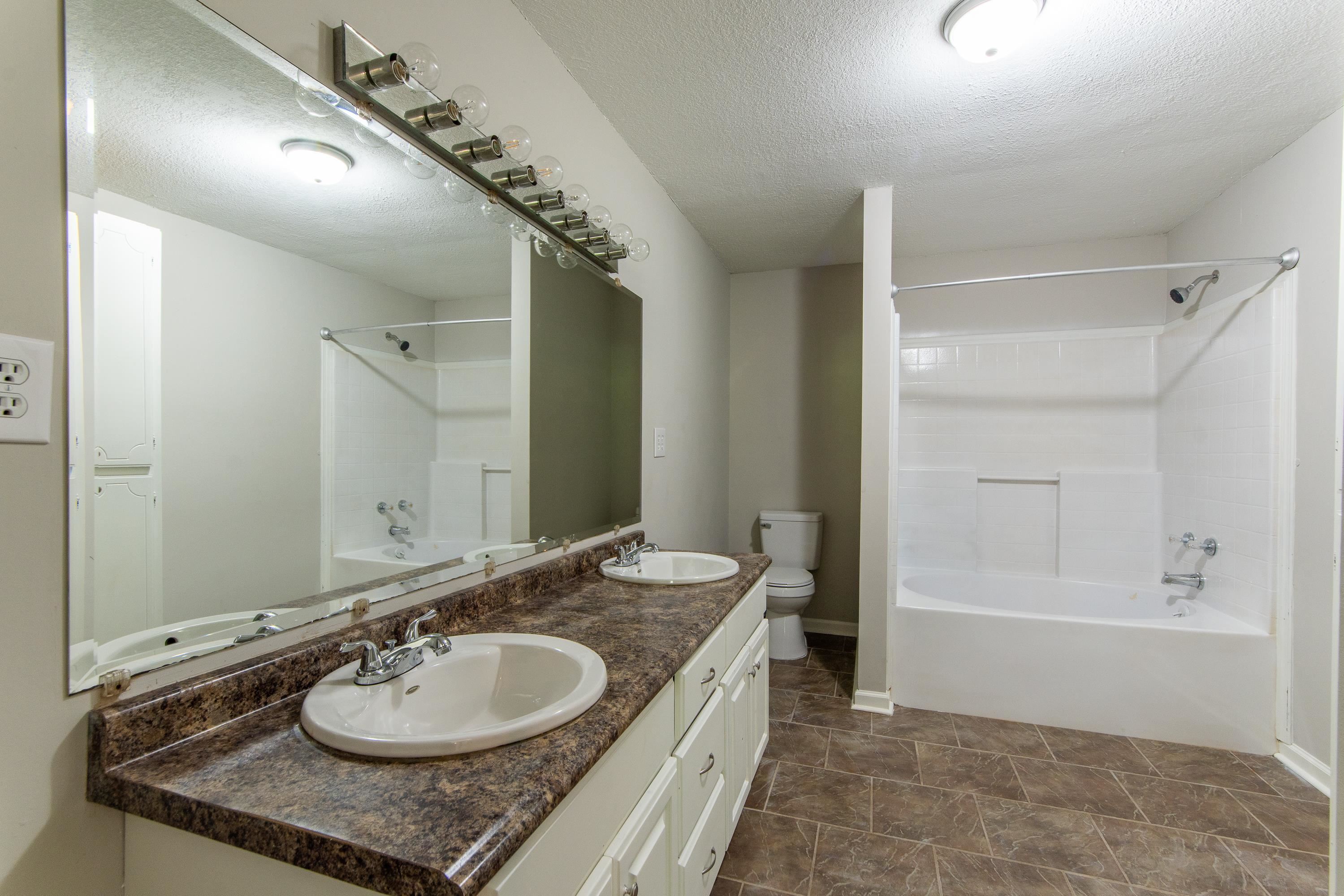 1020 County Road 600 Corinth, MS 38834 - Photo 11 of 37 a bathroom with a granite countertop sink a mirror a vanity and shower