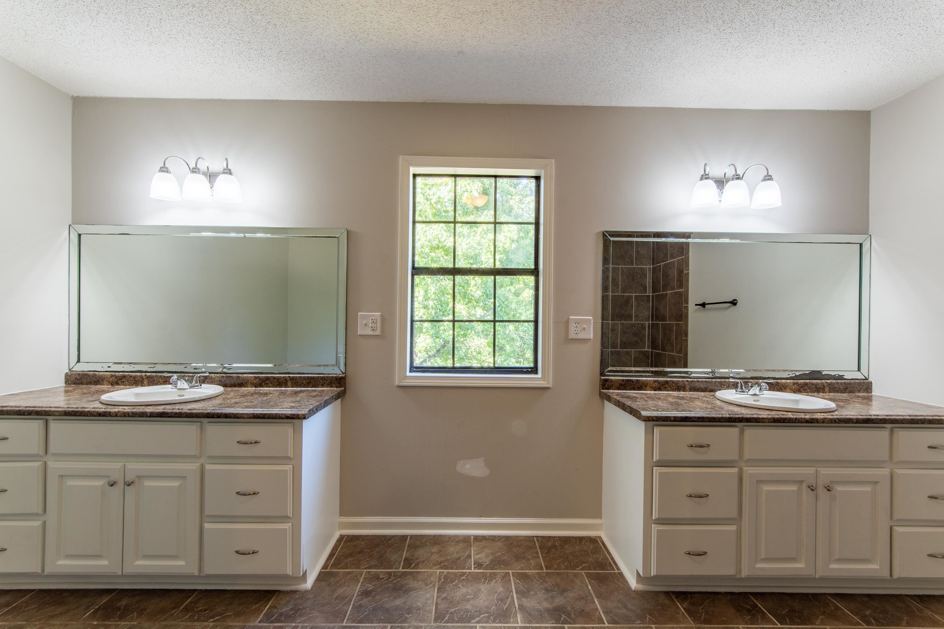 1020 County Road 600 Corinth, MS 38834 - Photo 28 of 37 a bathroom with a double vanity sink and mirror