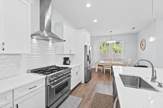 a kitchen with granite countertop a stove a sink and a white wooden cabinets