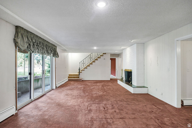 1365 Sumac Drive Logan, UT 84321 - Photo 31 of 66 Spacious room featuring broadloom carpeting, a white brick fireplace with a brass-toned insert and green stone hearth, and white vertical paneling