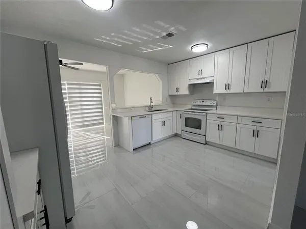 a kitchen with stainless steel appliances granite countertop a stove top oven a sink dishwasher and a refrigerator