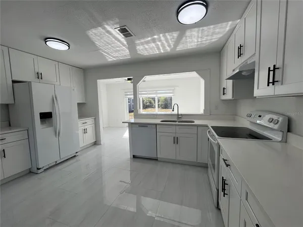 a kitchen that has a lot of white cabinets and stainless steel appliances