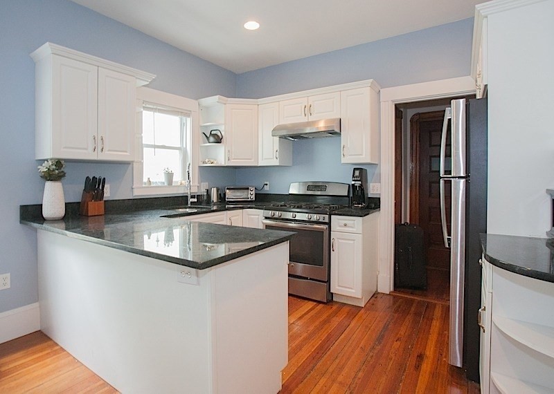 a kitchen with granite countertop a sink cabinets stainless steel appliances and a window