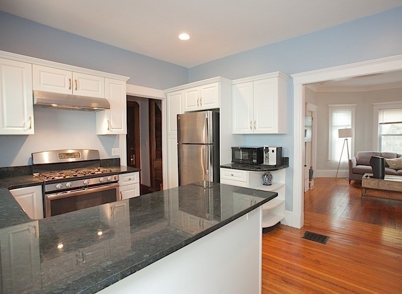 50 Holyoke Road, Unit 1 Somerville, MA 02144 - Photo 4 of 14 a kitchen with stainless steel appliances granite countertop a stove top oven a sink and white cabinets