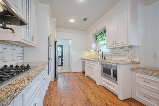 a large kitchen with stainless steel appliances granite countertop a lot of counter space and wooden floors