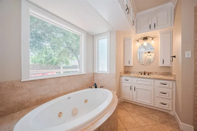 a bathroom with a bathtub a sink a mirror and a window