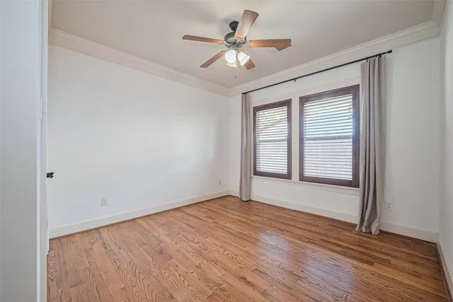 an empty room with wooden floor chandelier fan and windows