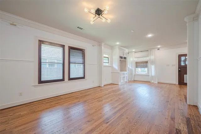 a view of an empty room with a window and wooden floor
