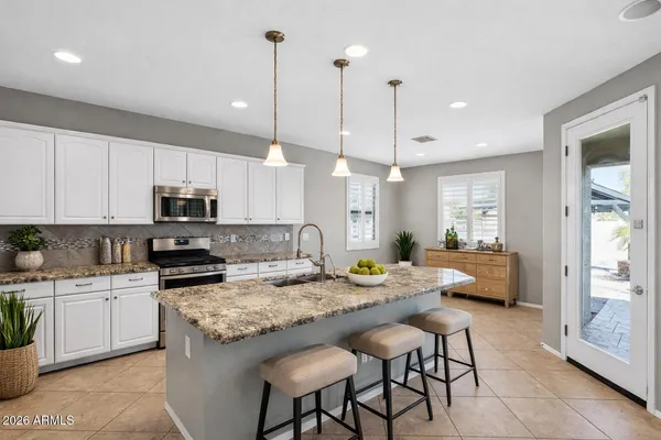a kitchen with granite countertop a stove and white cabinets