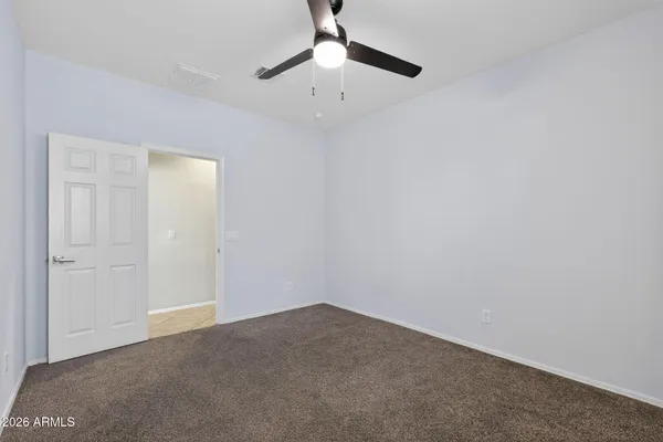 an empty room with wooden floor ceiling fan and windows