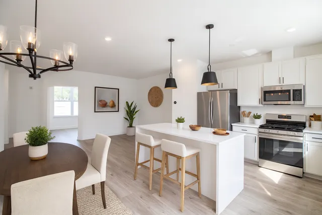 a kitchen with stainless steel appliances granite countertop a stove a sink a kitchen island a table and chairs