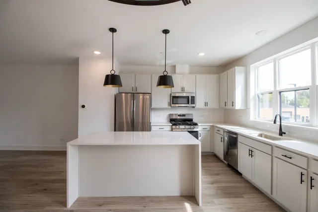 a large kitchen with stainless steel appliances kitchen island granite countertop a sink a stove and a refrigerator